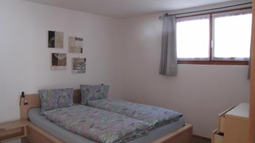 Bett in einem Zimmer mit Fenster in der Unterkunft Chesa Ovelin in Pontresina