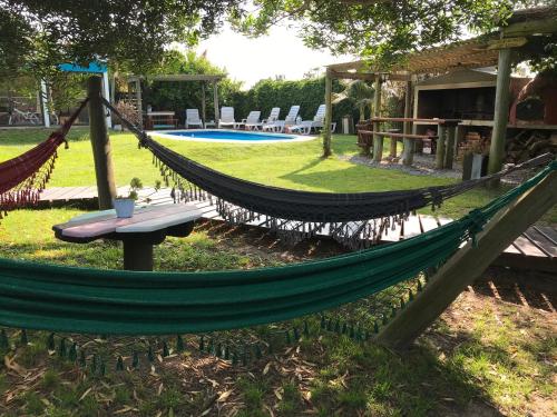 a hammock in a yard with a table and a pool at Posada de la Viuda in Punta Del Diablo