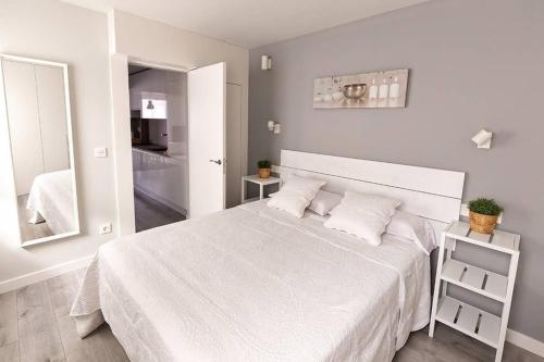 Dormitorio blanco con cama blanca y espejo en TOCANDO EL CIELO, en Burgos
