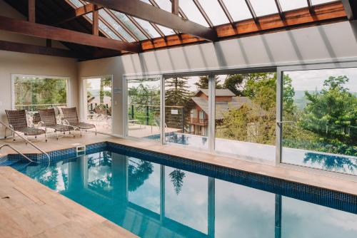 an indoor swimming pool with windows and a house at Hotel Jardins da Colina in Nova Petrópolis