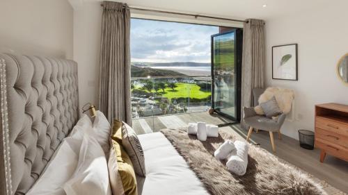 a bedroom with a bed and a large window at 2 Woolacombe West - Luxury Apartment at Byron Woolacombe, only 4 minute walk to Woolacombe Beach! in Woolacombe