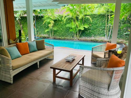 a patio with couches and a table and a pool at Alinta Villa 1 in Sanur