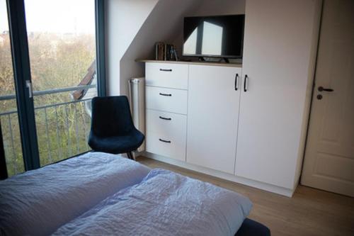 Schlafzimmer mit einem Bett, einem TV und einem Stuhl in der Unterkunft Eiland Wangerooge in Wangerooge