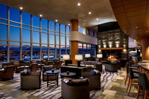a lobby of a hotel with tables and chairs and a fireplace at Fairmont Vancouver Airport In-Terminal Hotel in Richmond