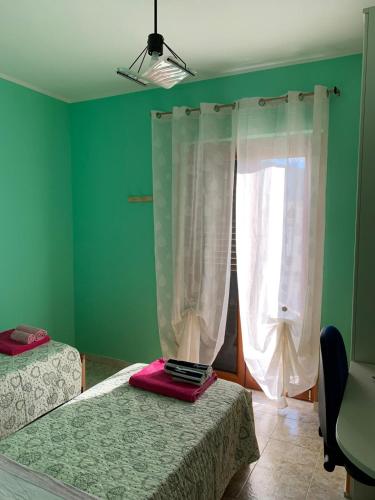 a green room with two beds and a window at B&B RoMa Atella in Atella