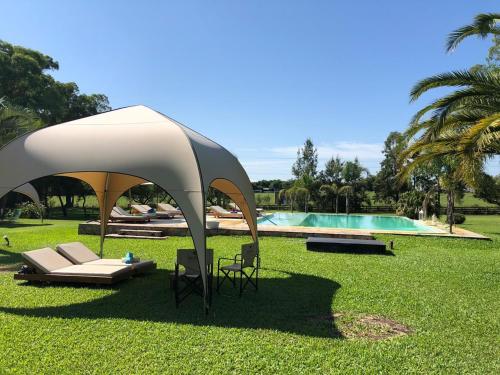 a gazebo in the grass next to a pool at Noha Casa de Campo in Colón