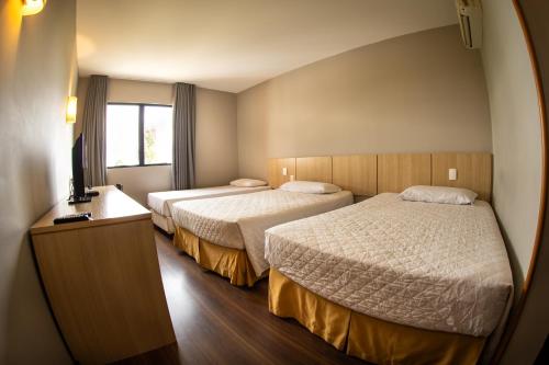 a hotel room with two beds and a television at Hotel Campo Largo Express in Campo Largo