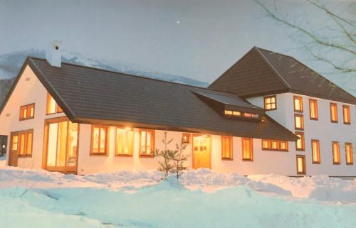 a house with snow in front of it at The Joint in Hakuba