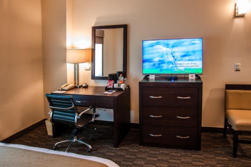 a hotel room with a desk with a television and a bed at Best Western Plus Chihuahua Juventud in Chihuahua