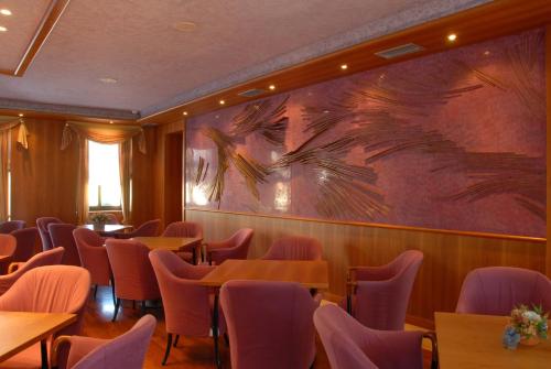 a restaurant with tables and chairs and a large painting on the wall at Grand Hotel Astoria in Lavarone