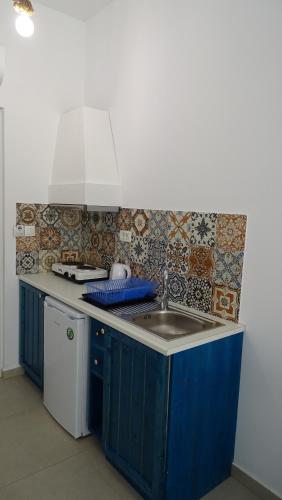 a kitchen with blue cabinets and a sink at Filoxenia Apartments & Studios in Theologos