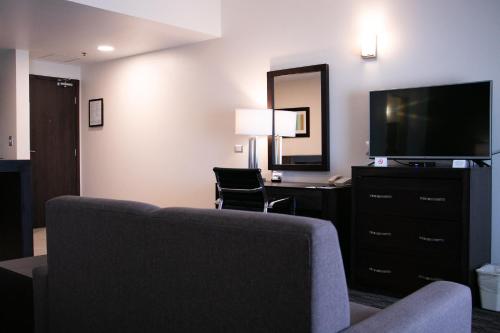 a living room with a couch and a television at Best Western Plus Chihuahua Juventud in Chihuahua
