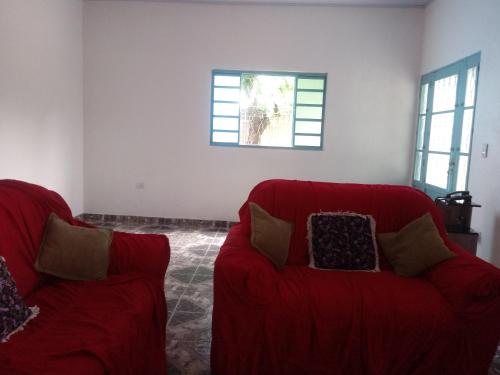 a living room with two red couches and a window at Casa Beija-flor in Cavalcante