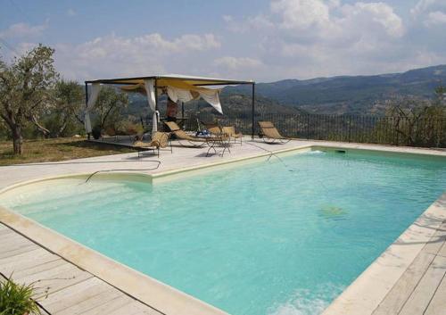 a large swimming pool with chairs and a umbrella at Villa Poggio Aperto in Seggiano