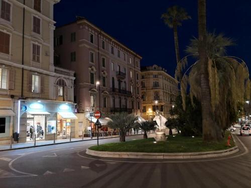 a city street at night with buildings and palm trees at Petit avec classe Sanremo in Sanremo