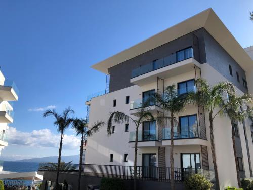 a building with palm trees in front of it at Andon Lapa Hotel & Spa in Sarandë