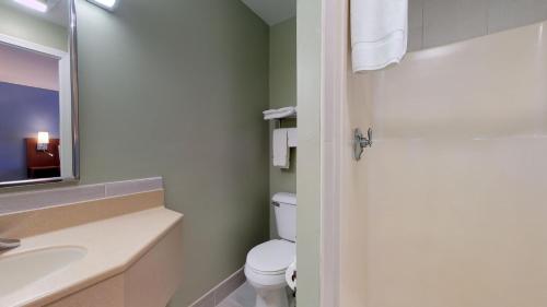 a bathroom with a toilet and a sink and a mirror at Scarborough Beach Motel in Narragansett