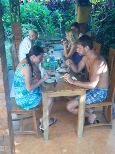 a group of people sitting around a wooden table at Nami House in Ubud