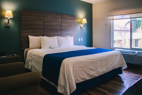 a hotel room with a large bed with a blue blanket at Best Western Plus Chihuahua Aeropuerto in Chihuahua