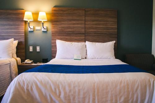 a hotel room with a large bed with white sheets at Best Western Plus Chihuahua Aeropuerto in Chihuahua