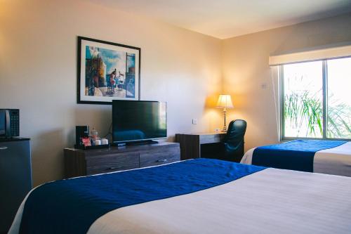 a hotel room with two beds and a flat screen tv at Best Western Plus Chihuahua Aeropuerto in Chihuahua