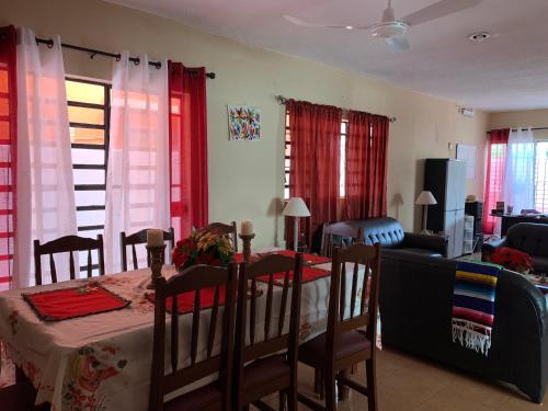 uma sala de estar com uma mesa e cadeiras e cortinas vermelhas em casa alegria em Mérida