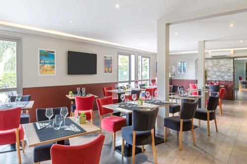 a restaurant with tables and chairs and a flat screen tv at Best Western Plus Hyères Côte D'Azur in Hyères