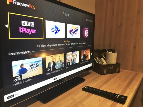 a television screen with a remote control on a table at Argyll Hotel in Bellochantuy