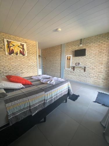 a bedroom with a bed and a brick wall at Pousada Manga Azul in Barra de Camaratuba