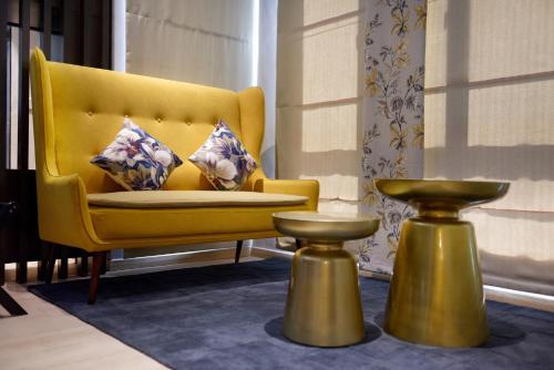 a yellow chair with two pillows and a table at Sojourn Spa Hotel Ipoh in Ipoh
