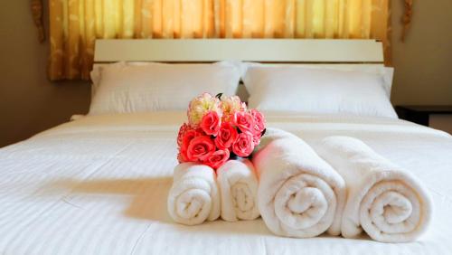 Una cama con toallas y rosas. en Narakorn House, en Buriram
