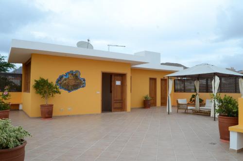 a yellow house with a patio and an umbrella at Kira's Boutique Hotel in Mindelo