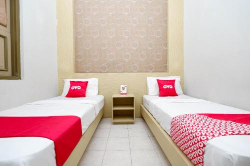 2 camas individuais num quarto com almofadas vermelhas em OYO 2436 Hotel Kencana em Tegal