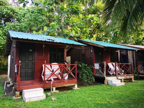 une petite maison rouge avec une terrasse couverte et 2 chaises dans l'établissement Puteri Salang Inn, à l'Île Tioman