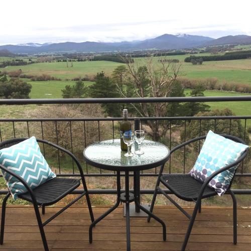 a table with two chairs and a glass of wine on a balcony at Rosewhite House in Myrtleford