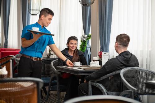 a man is holding a menu in a restaurant at Shining Central Hotel & Spa in Hanoi