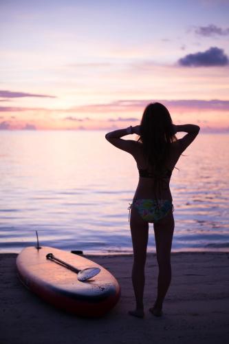 a woman standing on the beach next to a surfboard at -Musée Villa- in Nakijin