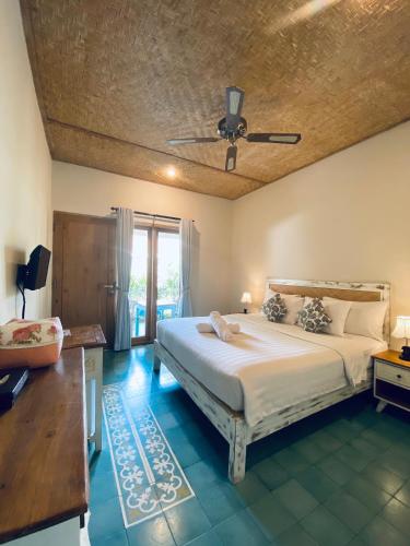 a bedroom with a large bed with a ceiling at Jukung Dua Guest House in Sanur