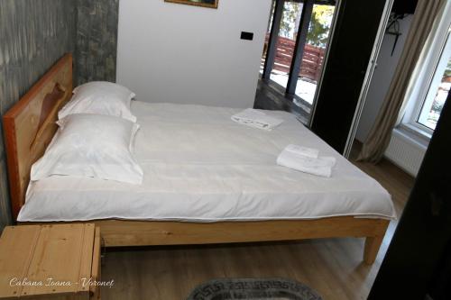 a bed with white sheets and pillows in a room at Cabana Ioana in Voronet