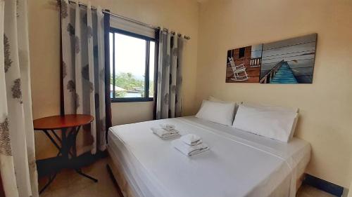 a bedroom with a white bed with a window at Tulip Apartment in Ormoc