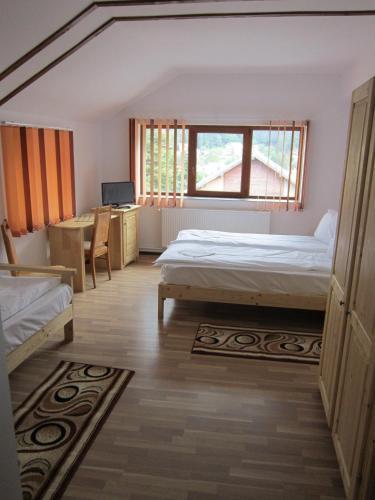 a bedroom with two beds and a desk and a window at Pensiunea Casa Maria in Buşteni