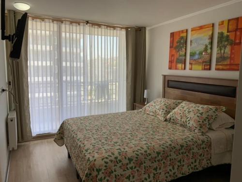 una camera da letto con un letto e una grande finestra di Departamento en el corazón de Viña del Mar a Viña del Mar