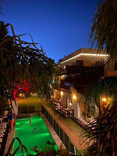a swimming pool in front of a house at night at Ayres Village Apart in Pinamar