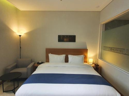 a hotel room with a large bed and a chair at Benikea Hotel Yangsan in Yangsan