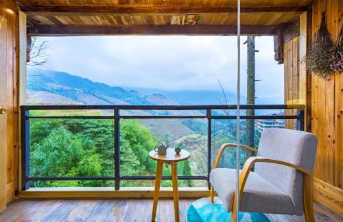 una habitación con una silla y una mesa y una ventana grande en Rice View Villa, en Longsheng