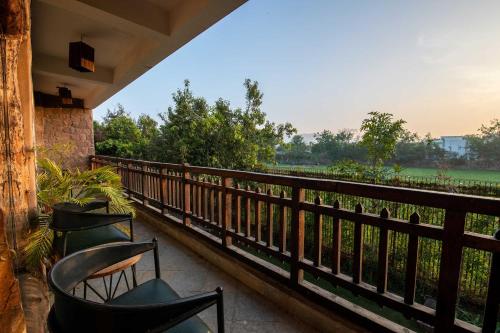 a balcony with two chairs and a view of a field at The Baagh Ananta Elite Ranthambore in Sawāi Mādhopur