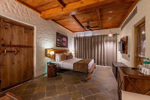 a bedroom with a bed and a wooden ceiling at The Baagh Ananta Elite Ranthambore in Sawāi Mādhopur