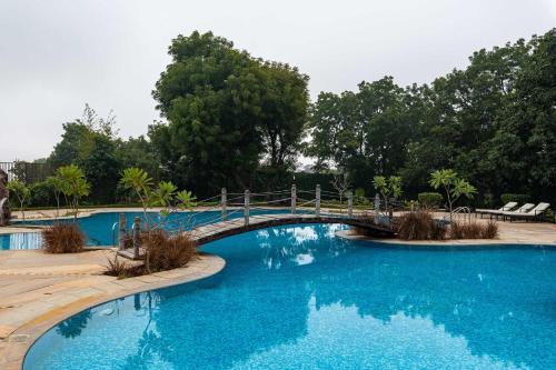 a bridge over a pool with blue water at The Baagh Ananta Elite Ranthambore in Sawāi Mādhopur