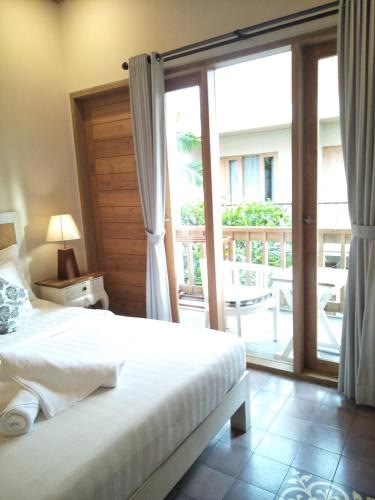 a bedroom with a bed and a sliding glass door at Jukung Guest House in Sanur