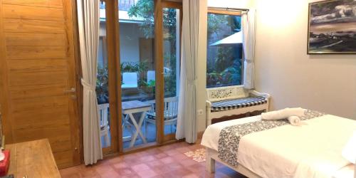 a bedroom with a bed and a window with a balcony at Jukung Guest House in Sanur